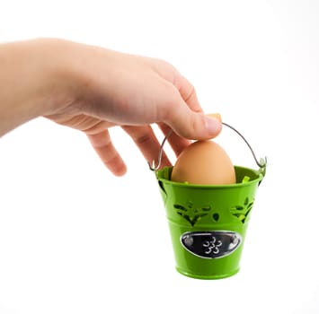 Hand holding green basket with egg, on white background.