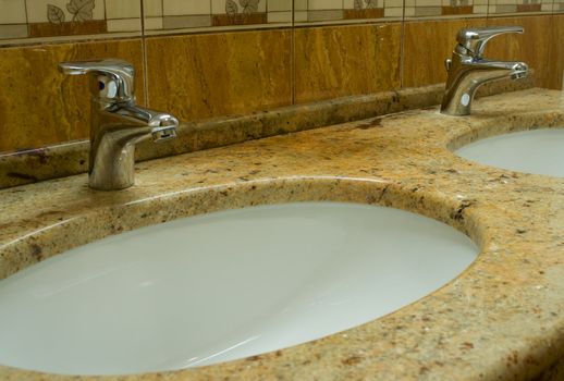 Washbowls in marble with closed water taps in bathroom.
