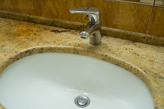 Washbowl in marble with closed water tap in bathroom.