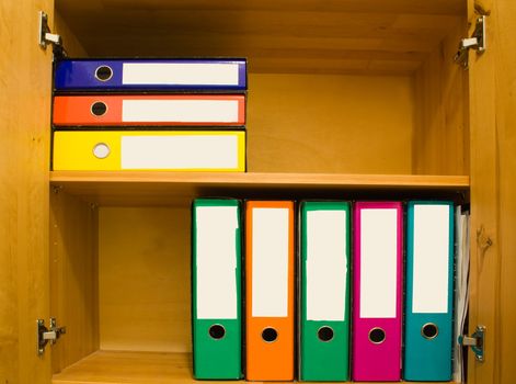 Colorful files with blank label in closet.