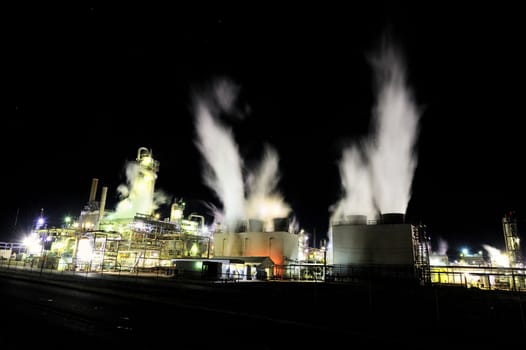 Graphic image of an industrial plant at night with steam flowing upward, shot at night with visible stars