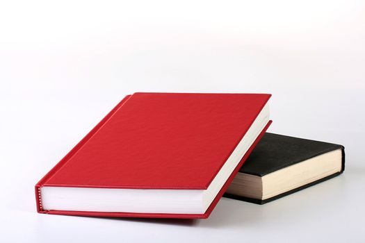 The red closed book lies on black both books on a white background.