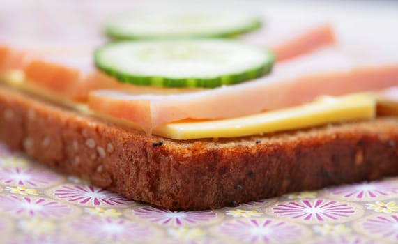 sandwich from pumpernickel bread with butter, ham and cucumber