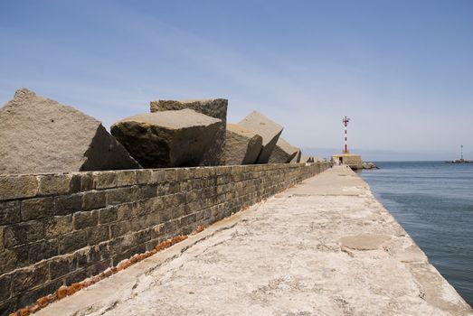 Perspective shot of pier in Montevideo, with small lighthouse in its end