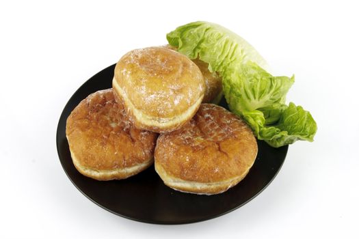 Contradiction between healthy food and junk food using doughnuts and lettace on a reflective white background 