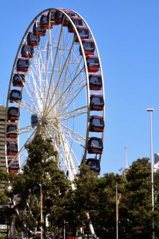 One, big ferris wheel with red gondolas with sky in the background. 