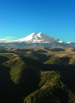 Two snow-covered mountain tops on a background of the blue sky.
          