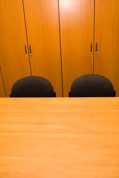 Detail of wooden closets, table and chairs in an office.