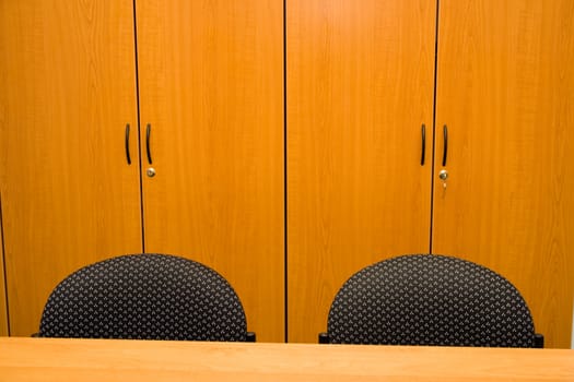 Detail of wooden closets, table and chairs in an office.