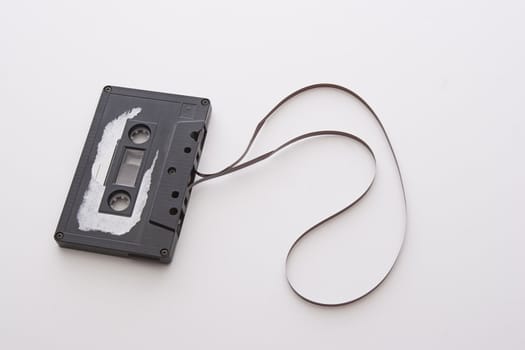 old tape cassette with cover sticker rip apart and part of the tape unrolled