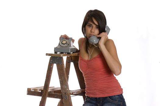 teenage girl standing on ladder talking on a old rotary phone with annoyed expression