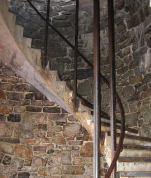 Upward shot of an old curved stairs next to a stone wall