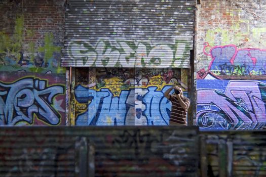 A photographer shooting in an area covered with graffiti.