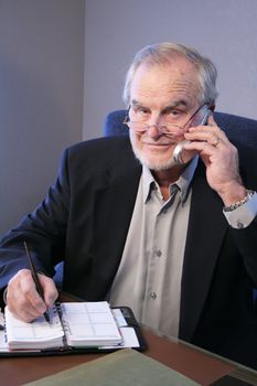 Mature Business Executiveon phone taking notes