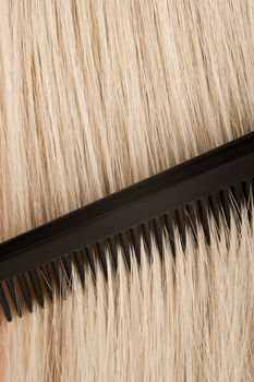 An old barbers comb running through blond hair.