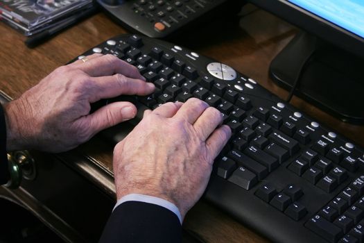 Elderly hands typing on keyboard
