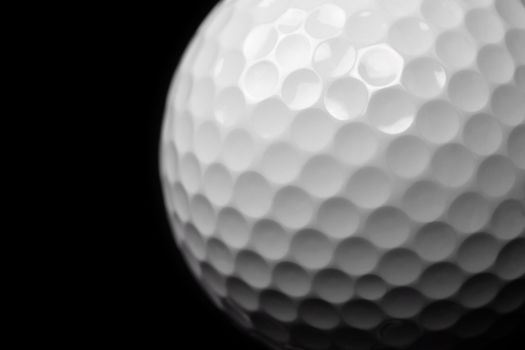 Macro image of a golf ball on black background. Shallow depth of field. Space for text.