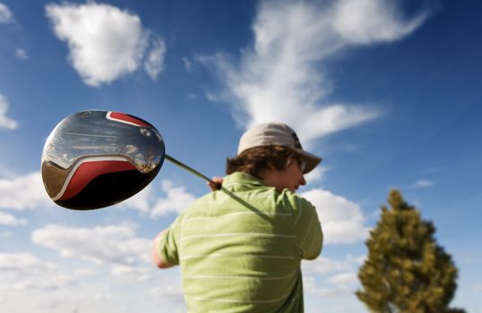 A golfer swinging a large wood (focus on golf club)