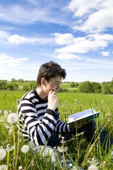 Boy reading a book on the grass. Time before examination