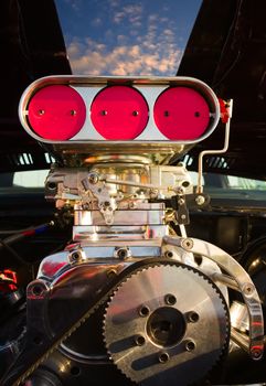 A supercharged engine with blue sky showing through the hood