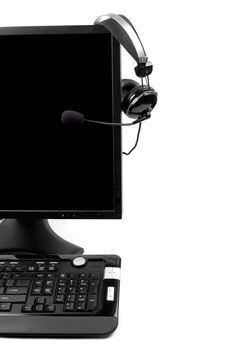 Computer with VOIP headset hanging on the screen, isolated on white background. Internet communications, VOIP (Voice Over Internet Protocol), call-center concepts. 