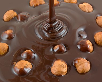 Chocolate flows on nuts. Tasty look - abstract food background