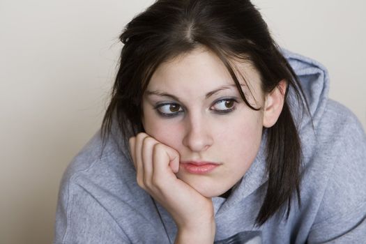 Bored teenager looking depressed, with a grey background