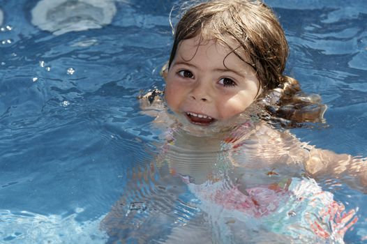 a cute little girl looking at pool water during the summer