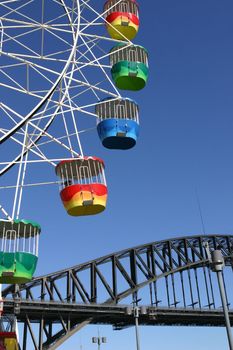 A colourful ferris wheel and the Sydney Harbour Bridge in the background.