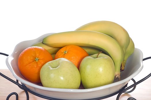 A white glass bowl full of bananas, oranges and apples, shot on a wooden board