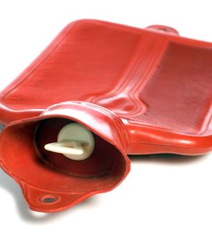 Closeup of a red hot water bottle with the plug in focus