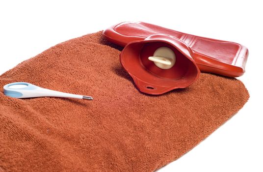 Three objects people commonly use when they are sick, including a hot water bottle, a thermometer, and a towel, isolated against a white background