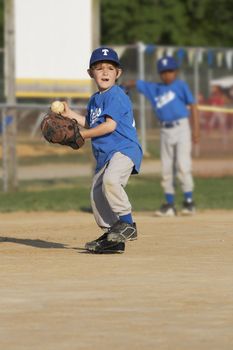 young boy on a baseball field with ball in hand