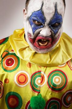 A nasty evil clown, angry and looking mean. Harsh lighting, focus on the teeth.