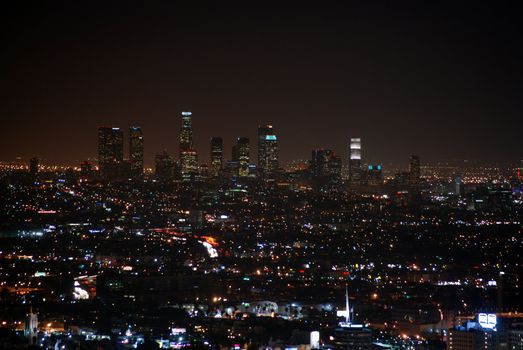 The lights of Downtown Los Angeles against the night sky.  Hollywood landmarks visible towards the bottom of the frame.