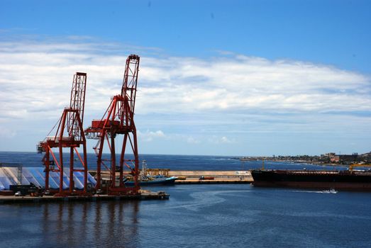 Container box cranes stand waiting during a bright sunny day at the port.