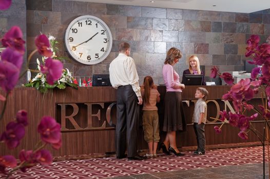 Happy family checking in at the reception desk 