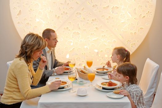Happy family enjoying meal sitting at restaurant table