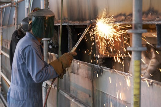 a worker using a torch to burn steel