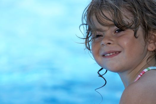 a young girl looking at camera buy a pool