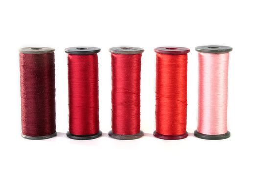 Colour threads for an embroidery on a white background. Threads on coils for industrial use.