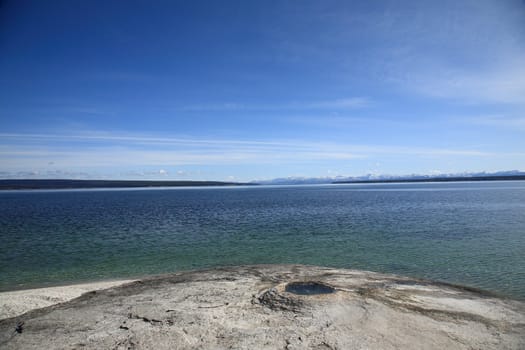 Yellowstone Lake, snow capped mountains and geyser.