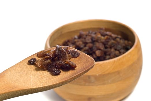 A wooden spoon full of raisins show of an ingredient for cookies or something, shot on white