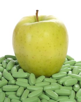 Concept image of an apple sitting on a bunch of vitamins to show that this fruit is full of nutrients