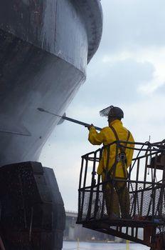 worker water blasting hull of ship