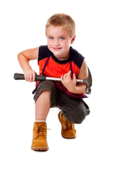 Cute young boy holding heavy duty hammer on his lap while squatting, isolated.