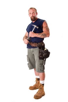 Big Caucasian guy with tattoos standing with hammer in his hands and wearing a tool belt, isolated.