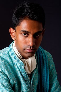 Beautiful face of an Indian Hindu young man with earring wearing blue Dhoti. Portrait of handsome Desi male, isolated.