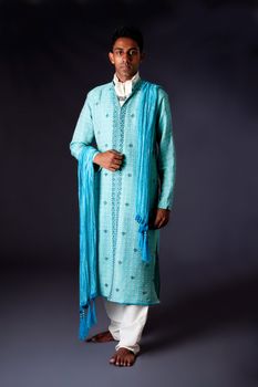 Beautiful authentic Indian hindu man in typical ethnic groom attire. Bengali male wearing a light blue agua decorated Dhoti with shawl.