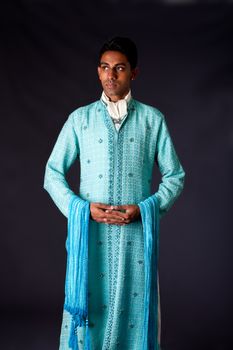 Beautiful authentic Indian hindu man in typical ethnic groom attire standing with hands together. Bangali male wearing a light blue agua decorated Dhoti with shawl.